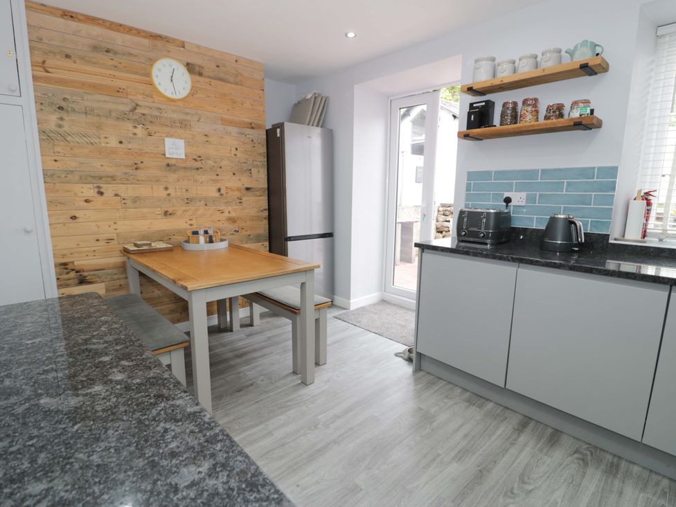 A kitchen with a dining table and benches at Y Bwthyn in Llanbedr