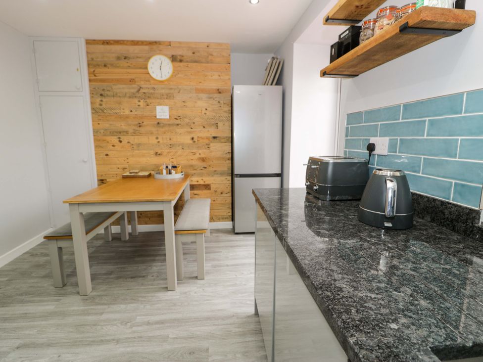 A kitchen with a table and refrigerator at Y Bwthyn Llanbedr