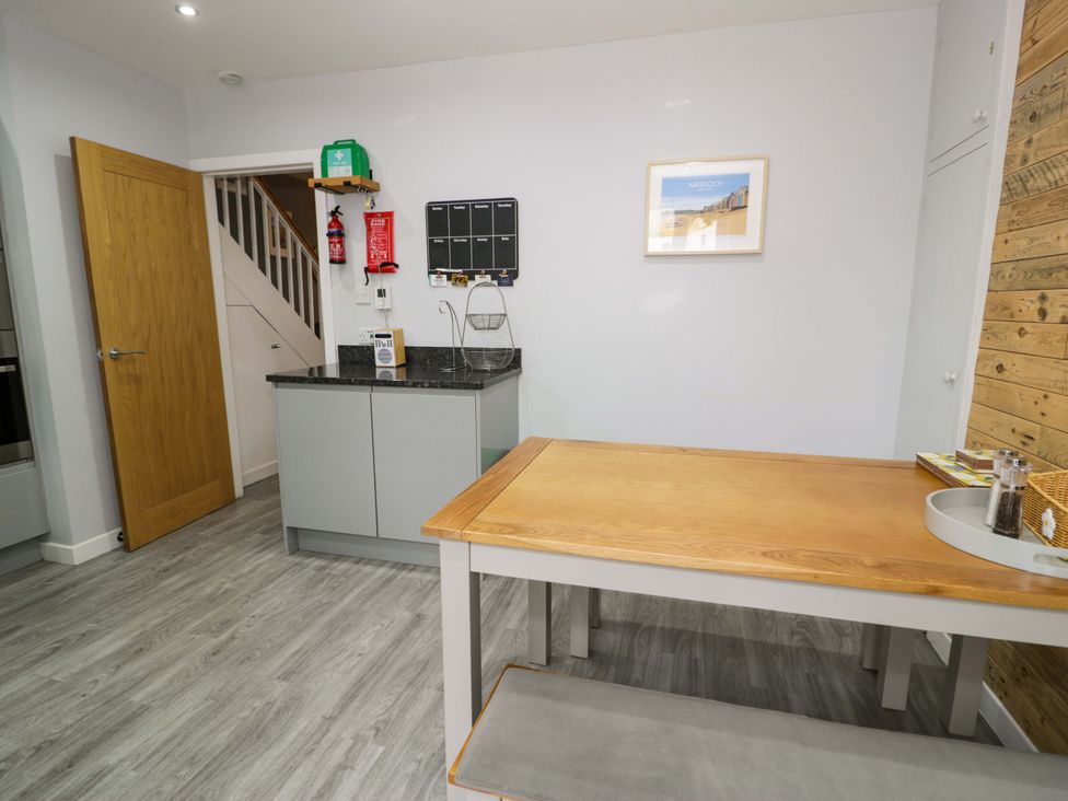 A kitchen with a table and cabinets at Y Bwthyn in Llanbedr