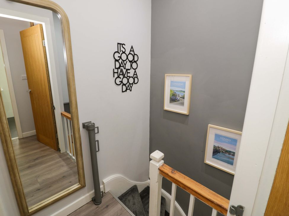 A hallway with a staircase and wall art at Y Bwthyn in Llanbedr
