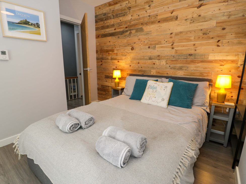 A bedroom with a bed and wooden wall paneling at Y Bwthyn in Llanbedr