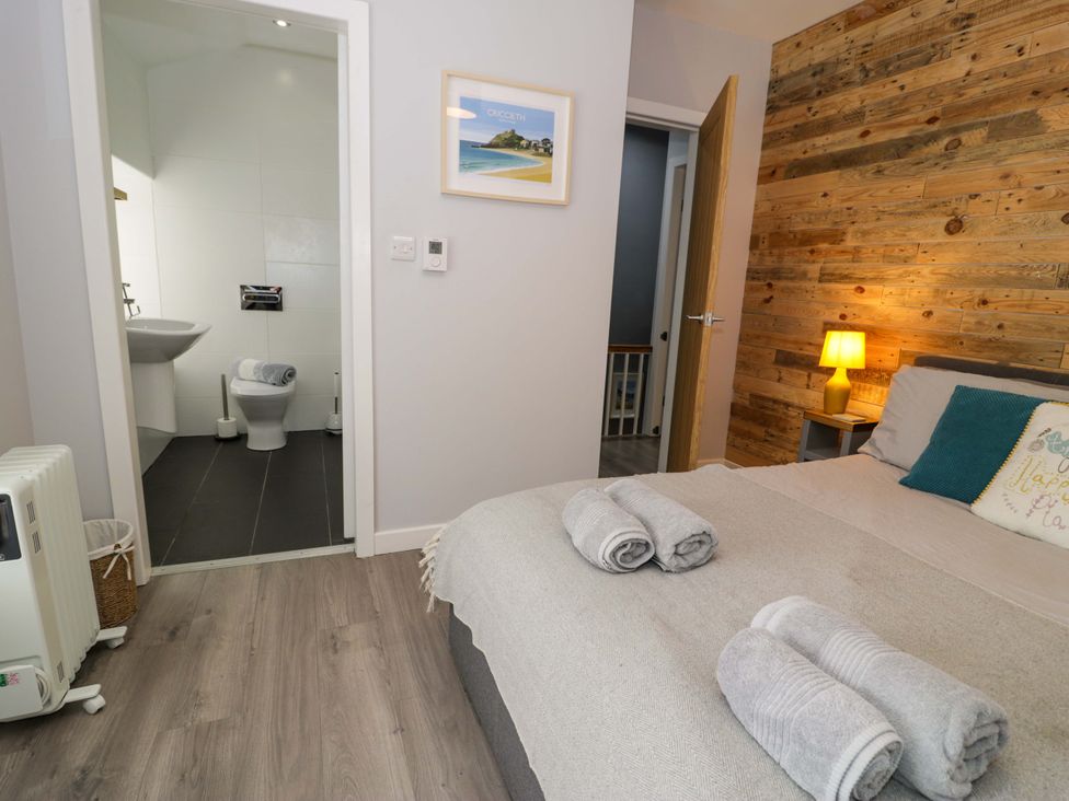 A bedroom with a bed and a bathroom view at Y Bwthyn in Llanbedr