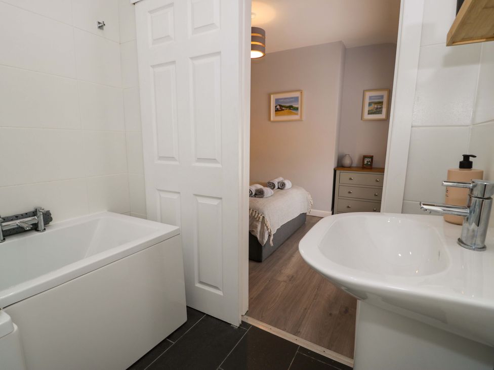 A bathroom with a bath tub and sink at Y Bwthyn in Llanbedr