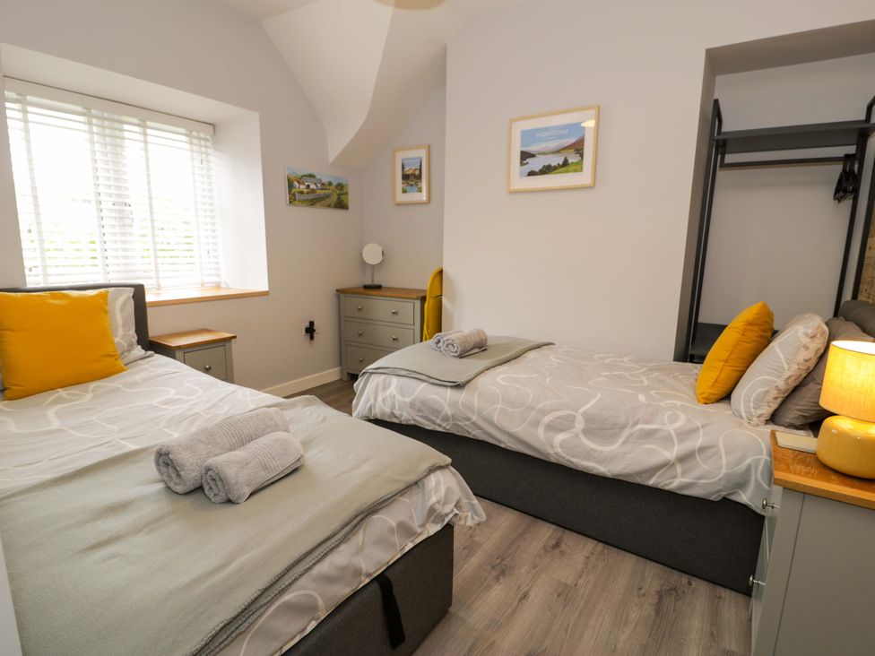 A bedroom with two single beds and a dresser at Y Bwthyn in Llanbedr