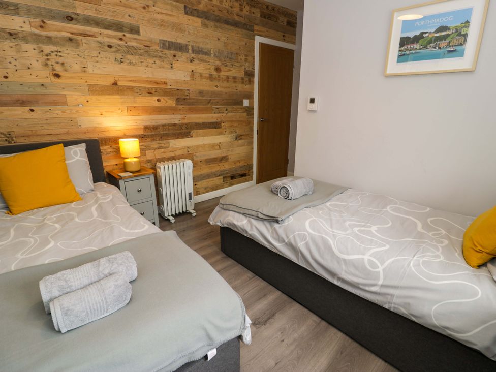A bedroom with two beds and a bedside table at Y Bwthyn in Llanbedr