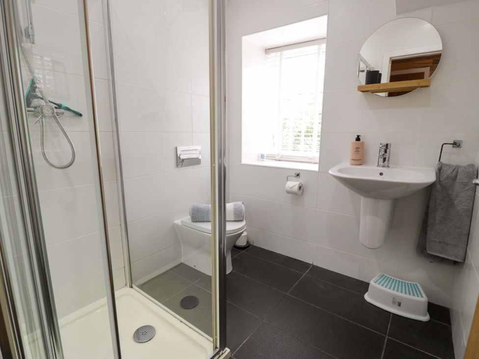 A bathroom with a shower, toilet, and sink at Y Bwthyn in Llanbedr