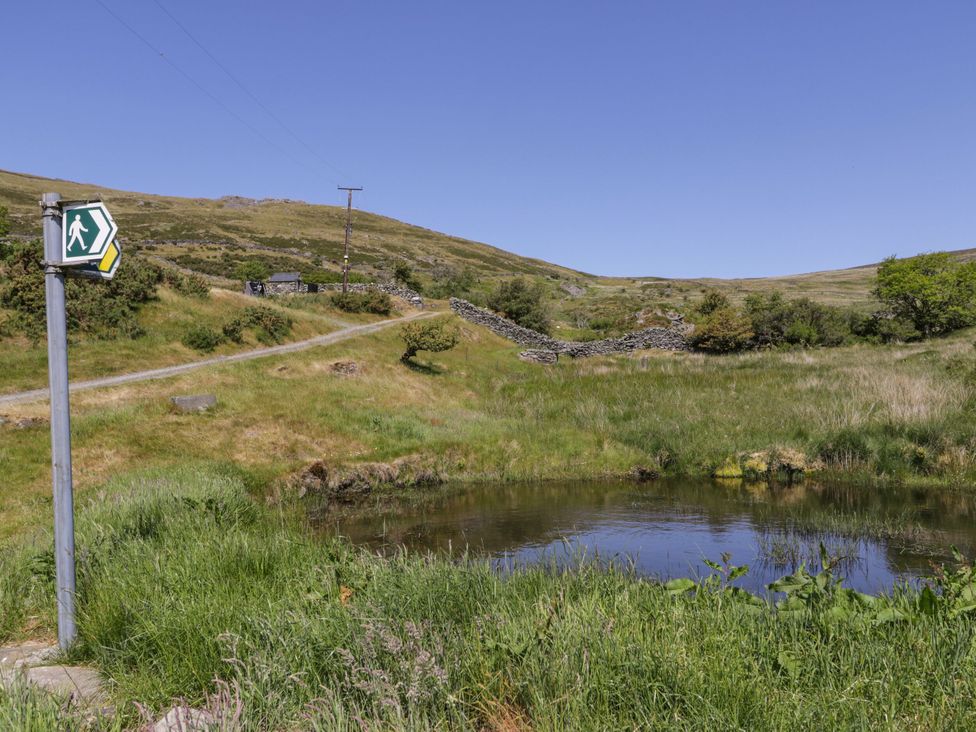 A path and water feature near a signpost at Y Bwthyn Llanbedr