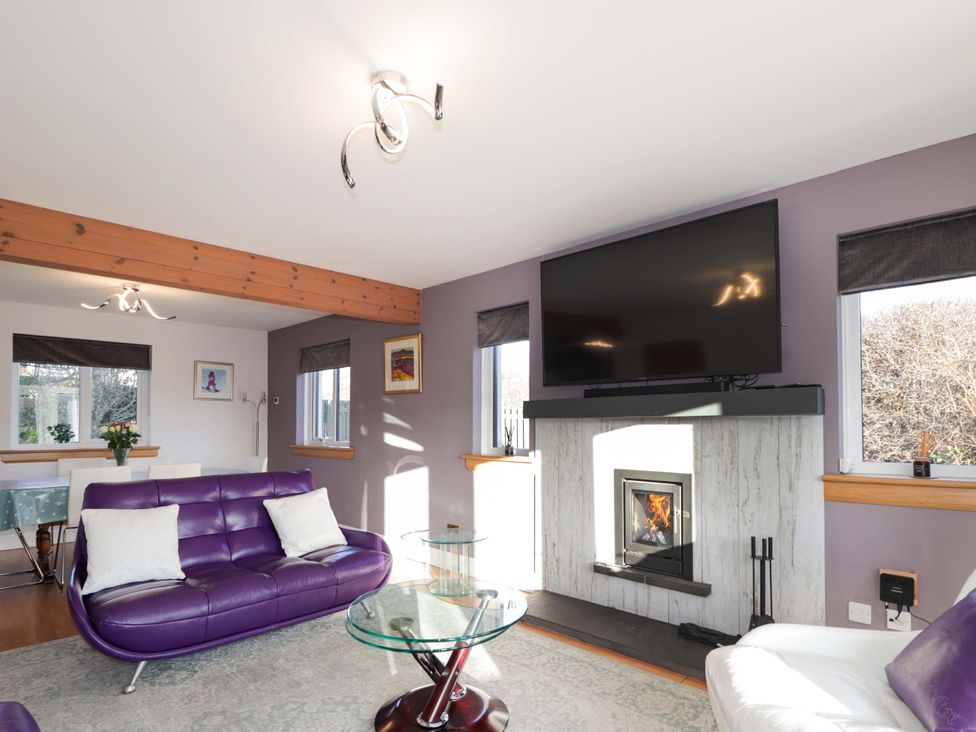 A living room with a purple sofa and tv mount at 3 Croftside in Aviemore