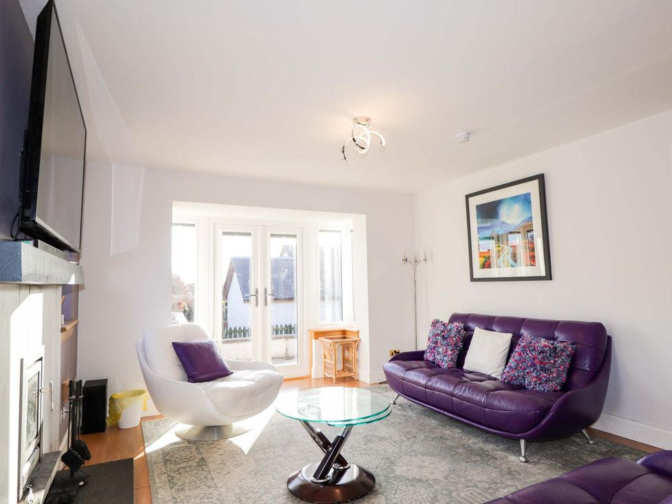 A living room with a purple sofa and coffee table at 3 Croftside in Aviemore