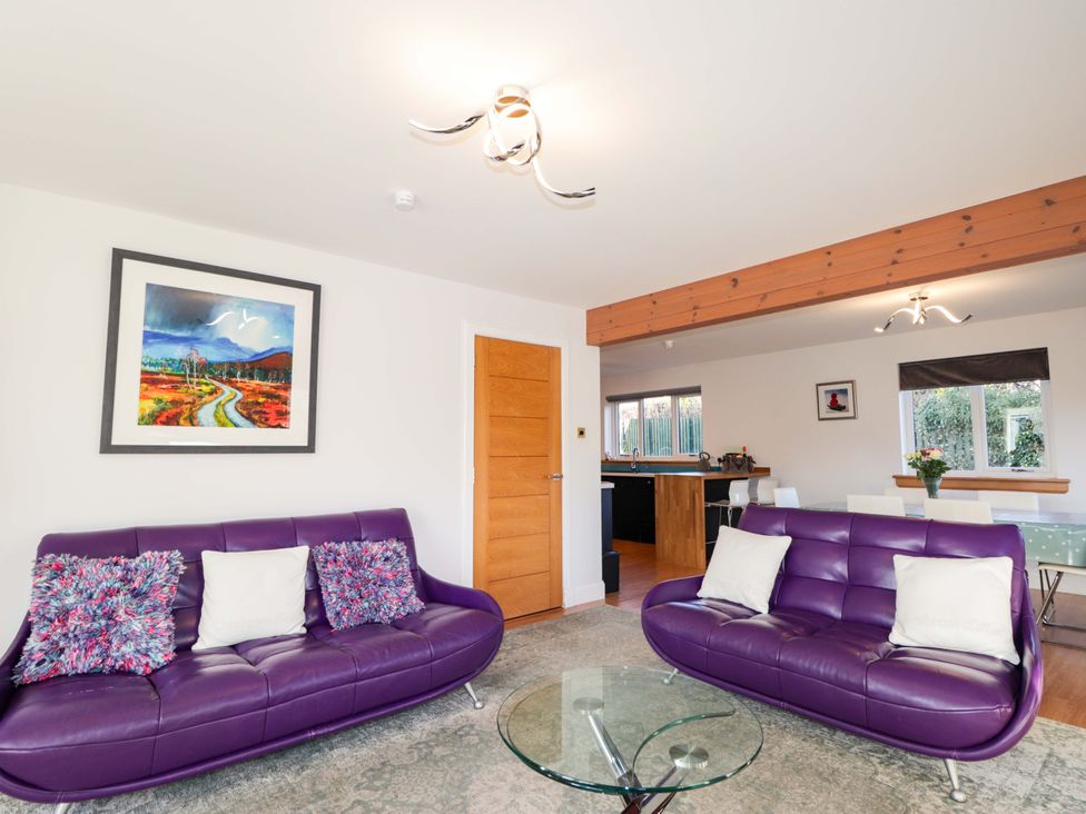 A living room with purple sofas and a glass table at 3 Croftside in Aviemore