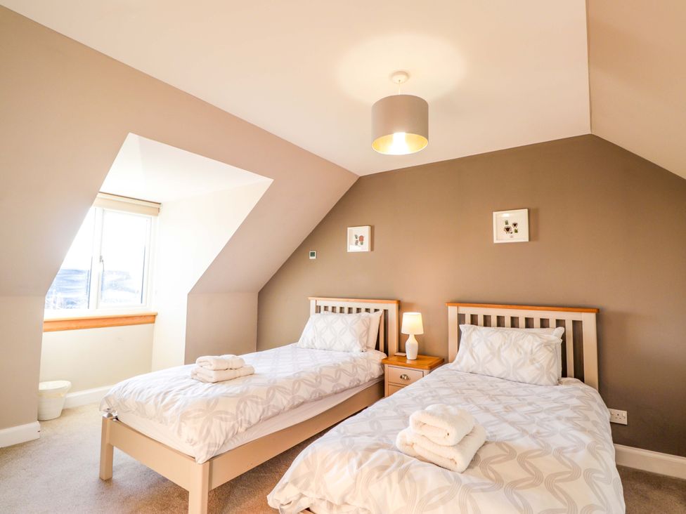 A bedroom with two beds and a window at 3 Croftside in Aviemore