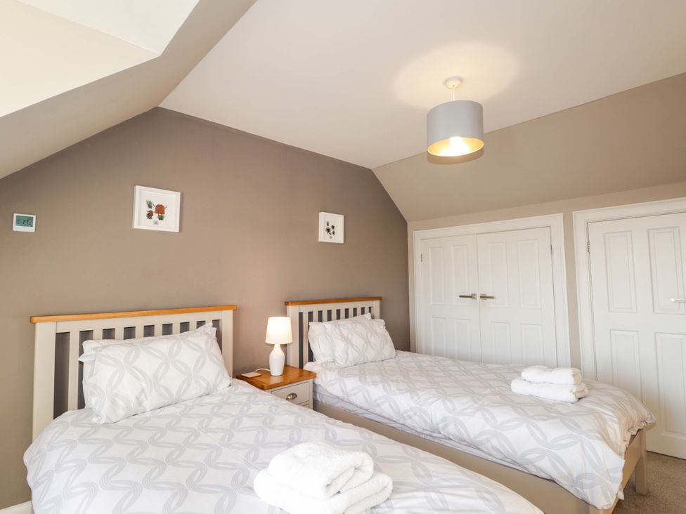 A bedroom with two beds and a nightstand at 3 Croftside in Aviemore