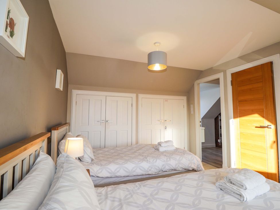A bedroom with two beds and wardrobes at 3 Croftside in Aviemore