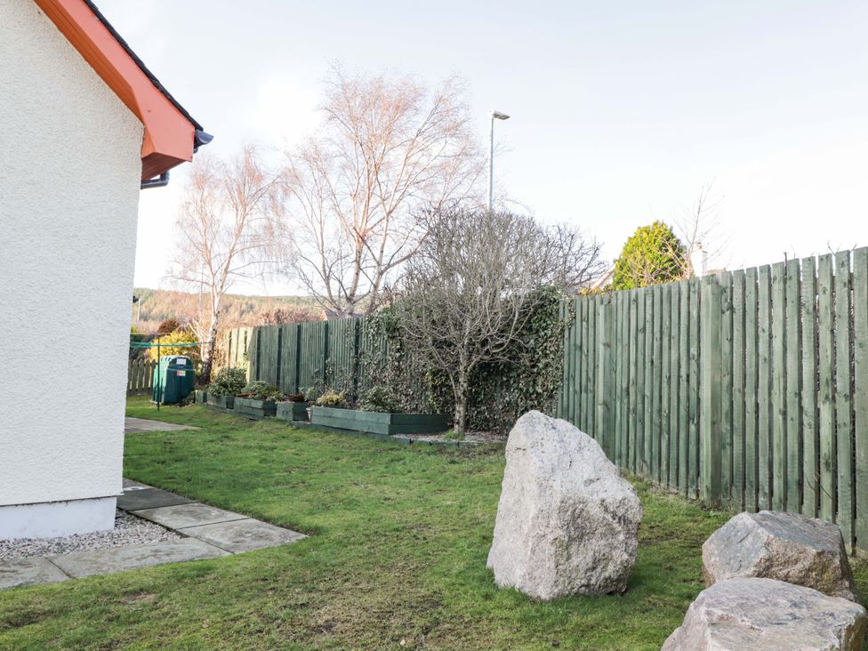 A garden with a tree and rocks at 3 Croftside, Aviemore