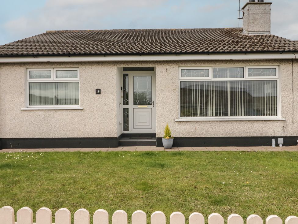 A front view of a house with a yard and fence at Hazel Cottage Portrush