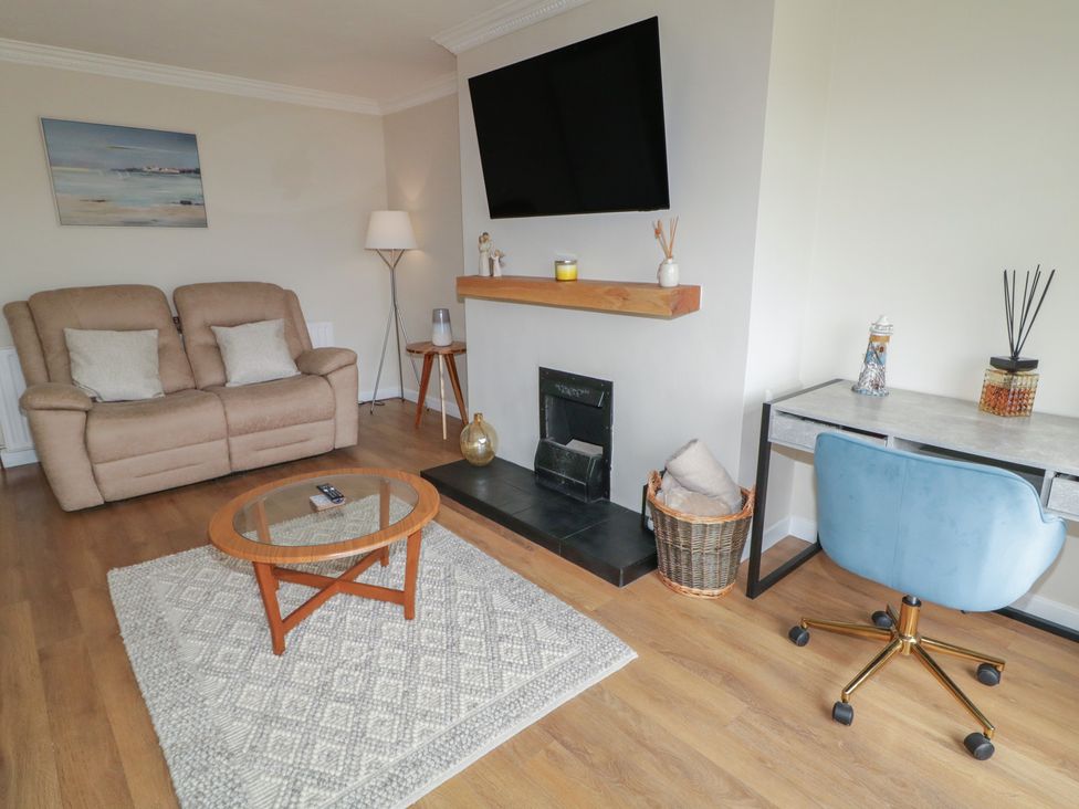 A living room with a sofa, coffee table, and desk at Hazel Cottage in Portrush