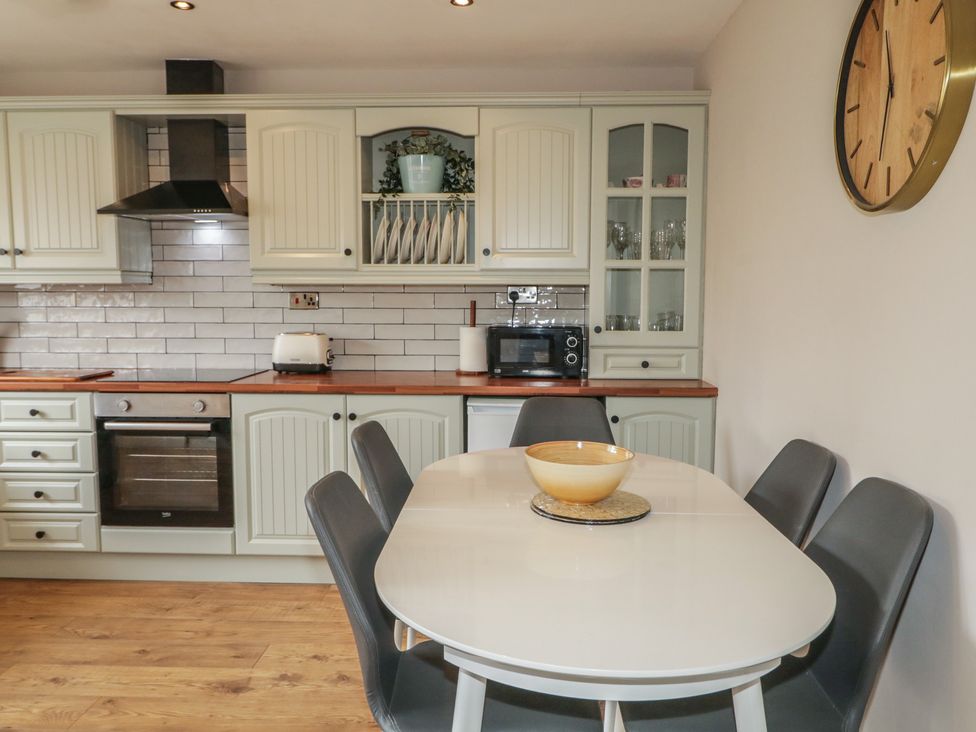 A kitchen with cabinets and a dining table at Hazel Cottage in Portrush