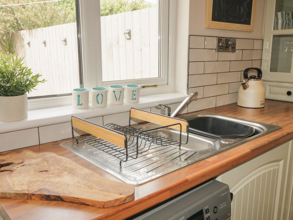 A kitchen with a sink and draining rack at Hazel Cottage in Portrush
