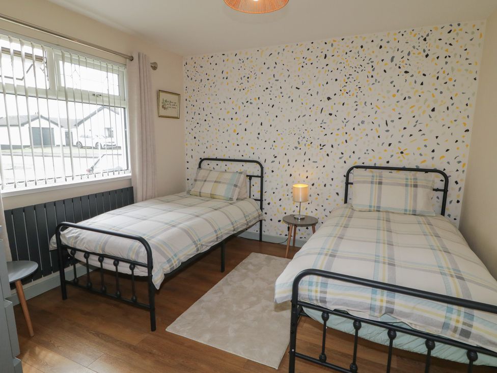 A bedroom with two beds and a bedside table at Hazel Cottage in Portrush