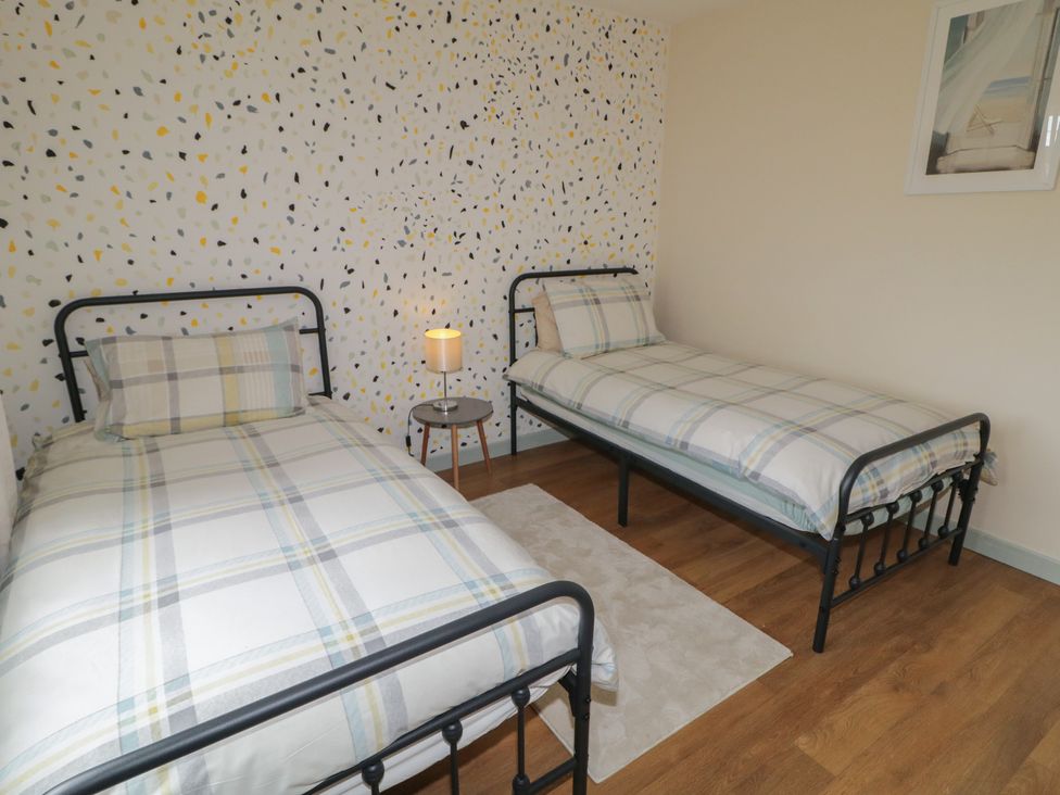 A bedroom with two single beds and a bedside table at Hazel Cottage in Portrush