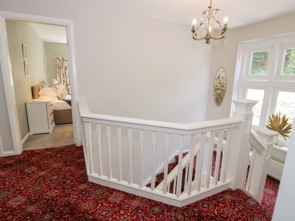 A staircase with a chandelier and a mirror at Pengwern in Llanrwst