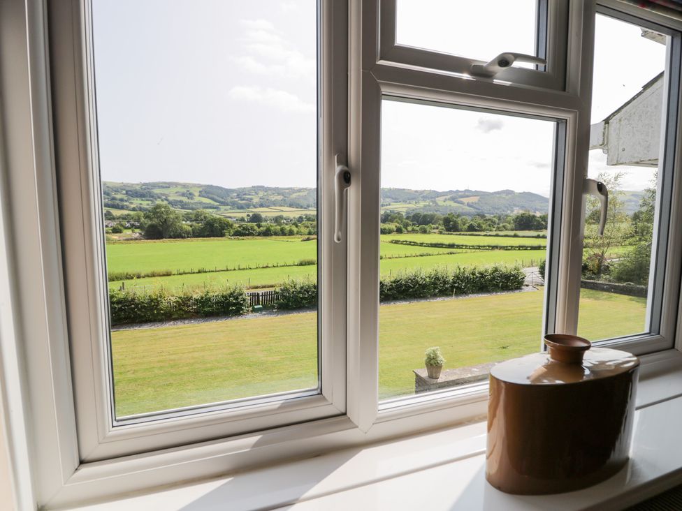 A view from a window showing fields and mountains at Pengwern in Llanrwst