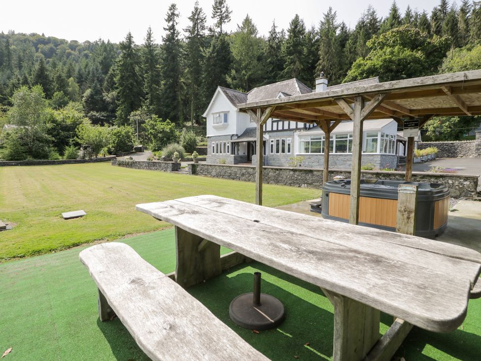 An outdoor area with a table and hot tub at Pengwern in Llanrwst