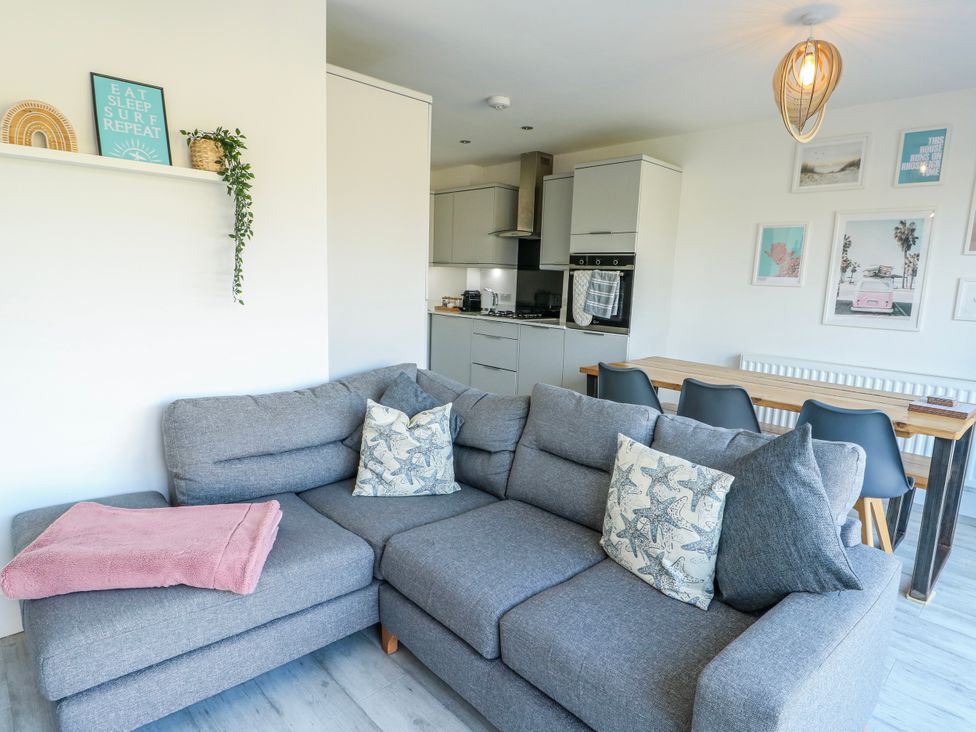 A living room with a sofa and dining area at Dune Retreat Llanfaelog near Rhosneigr