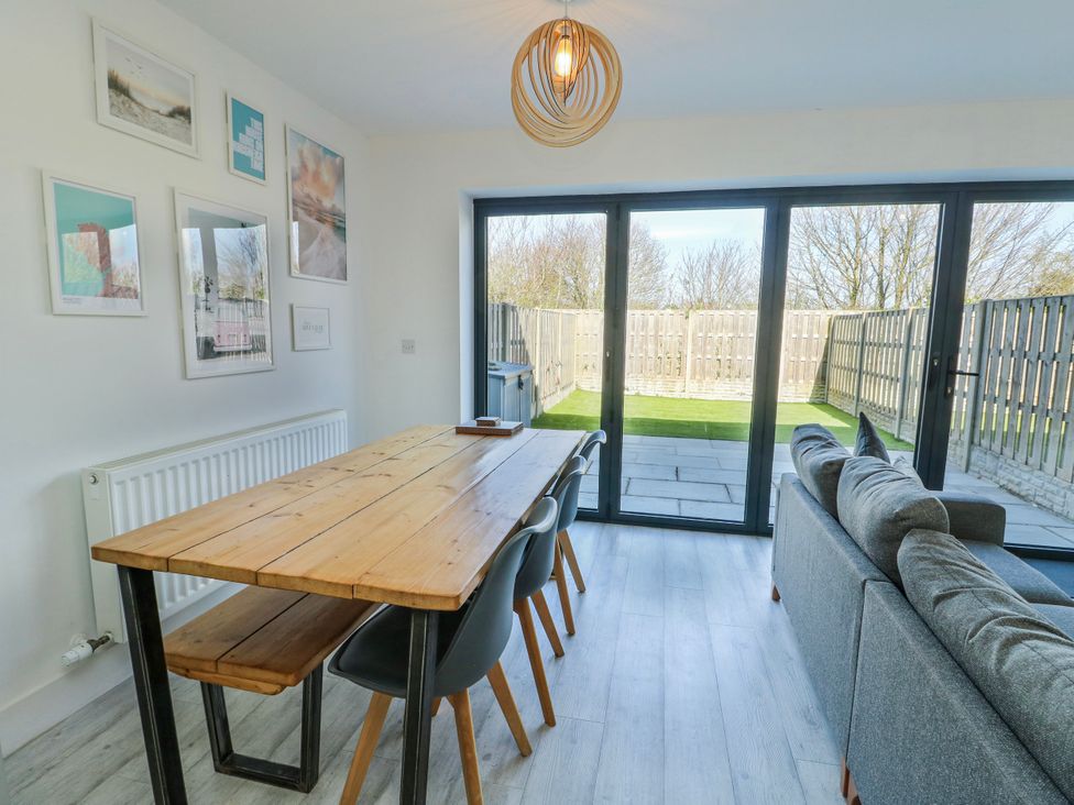 A dining room with a table and chairs at Dune Retreat in Llanfaelog near Rhosneigr