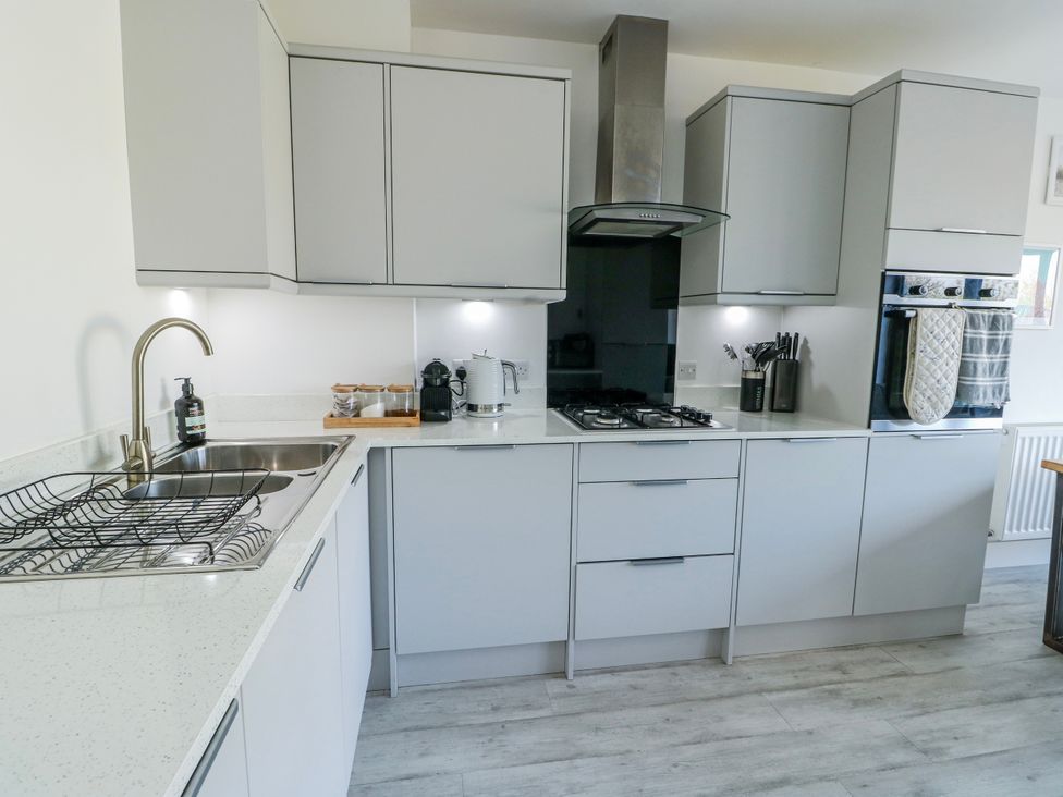 A kitchen with cabinets and appliances at Dune Retreat in Llanfaelog near Rhosneigr