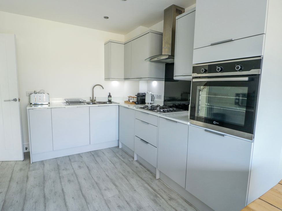 A kitchen with grey cabinets and appliances at Dune Retreat in Llanfaelog near Rhosneigr