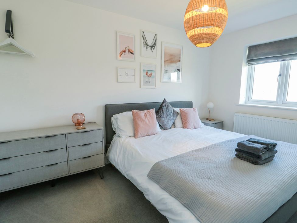 A bedroom with a bed and dresser at Dune Retreat in Llanfaelog near Rhosneigr