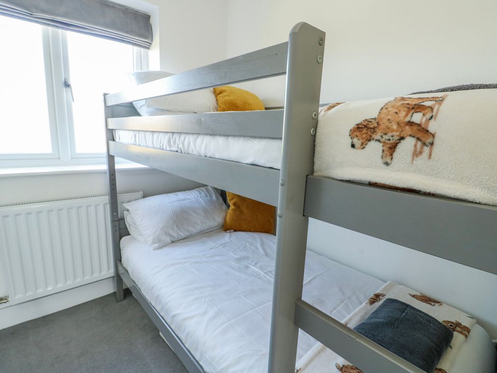 A bunk bed with pillows and blankets in a bedroom at Dune Retreat in Llanfaelog near Rhosneigr