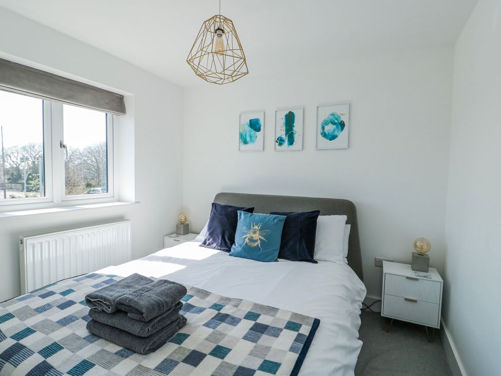 A bedroom with a bed, a side table and artwork at Dune Retreat in Llanfaelog near Rhosneigr