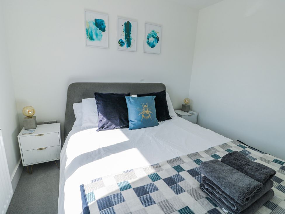 A bedroom with a bed and bedside tables at Dune Retreat in Llanfaelog near Rhosneigr