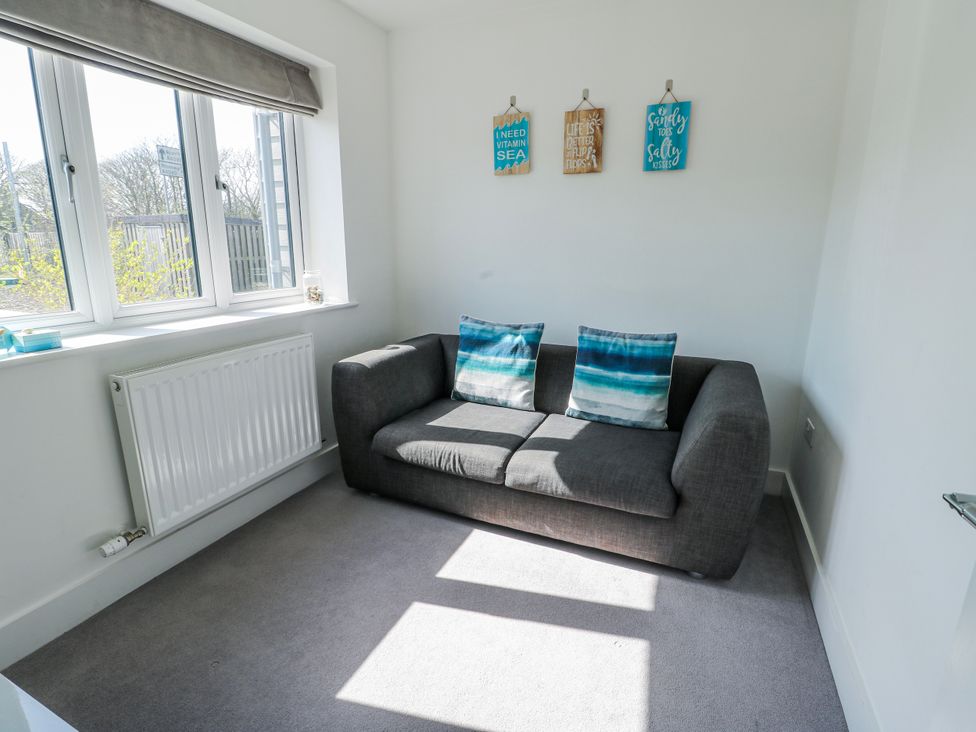 A snug with a sofa and decorative signs at Dune Retreat in Llanfaelog near Rhosneigr