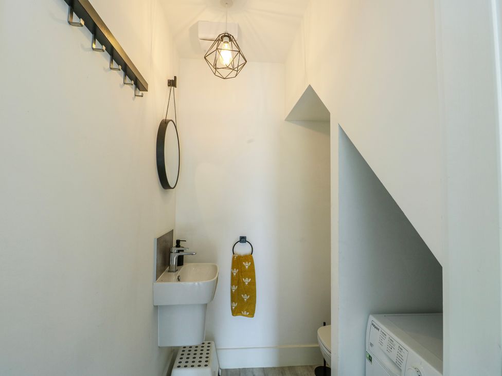 A bathroom with a sink, mirror, and toilet at Dune Retreat Llanfaelog near Rhosneigr