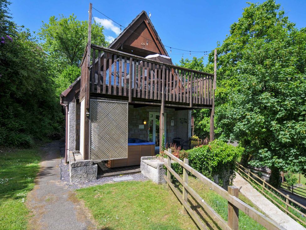 A two story house with a balcony and a wooden fence surrounded by trees at 59 Valley Lodge in Callington near Gunnislake