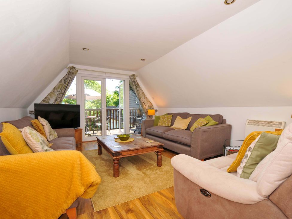 A living room with sofas a wooden coffee table and a TV near glass doors opening to a balcony at 59 Valley Lodge Callington near Gunnislake