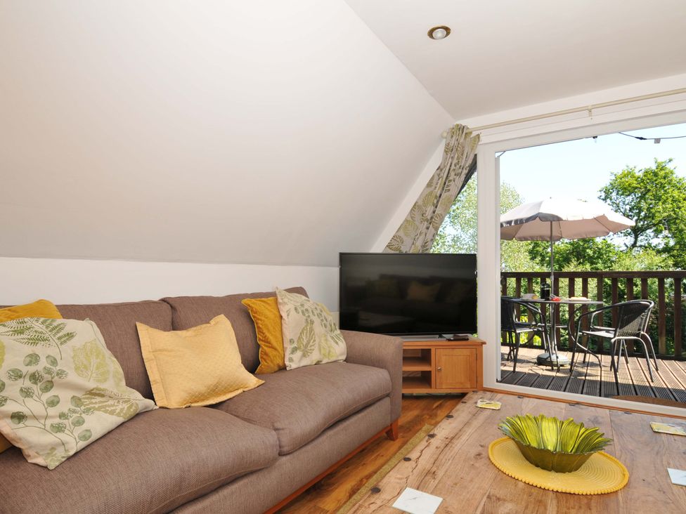 A living room with a brown sofa with cushions a wooden coffee table a TV and a balcony with a table and chairs at 59 Valley Lodge Callington near Gunnislake