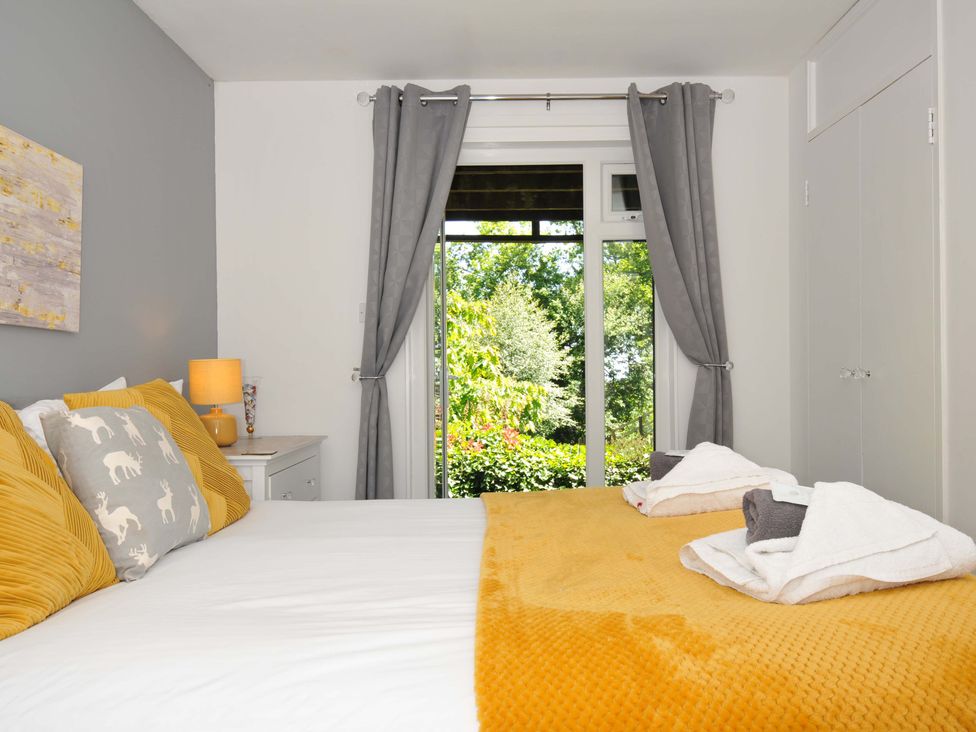 A bedroom with a bed with yellow and grey pillows and folded towels on a yellow blanket at 59 Valley Lodge in Callington near Gunnislake