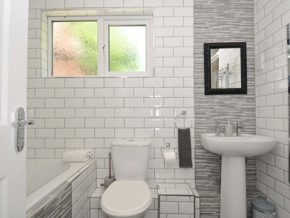 A bathroom with a toilet sink and bathtub with tiled walls at 59 Valley Lodge in Callington near Gunnislake