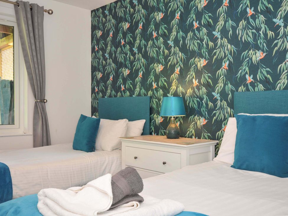 A bedroom with two single beds a white nightstand and a lamp at 59 Valley Lodge Callington near Gunnislake