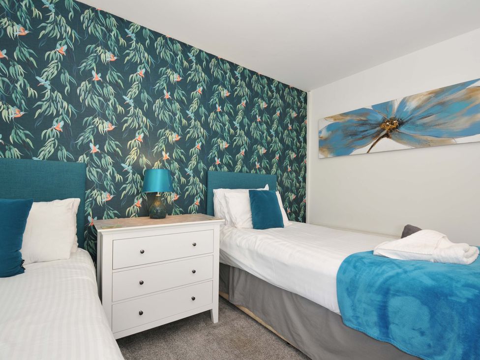 A bedroom with two single beds a white chest of drawers and a lamp at 59 Valley Lodge in Callington near Gunnislake
