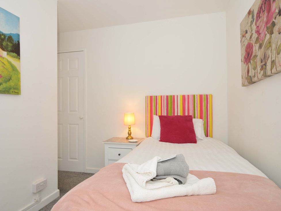 A bedroom with a single bed with striped headboard bedside table with lamp and paintings on walls at 59 Valley Lodge in Callington near Gunnislake