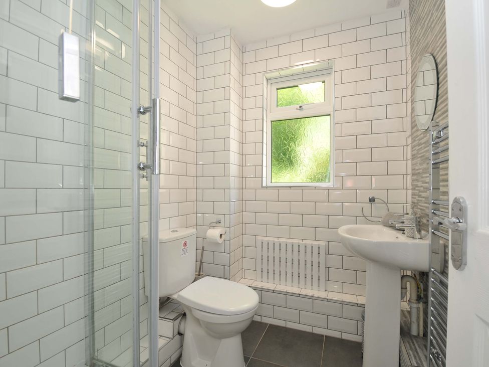 A bathroom with a shower cubicle toilet pedestal sink and a frosted window at 59 Valley Lodge in Callington near Gunnislake