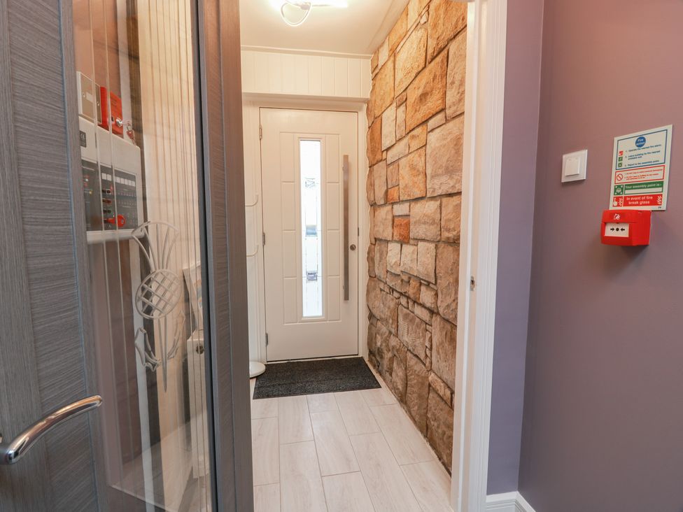 An entrance hall with a front door and stone wall at Shotts Cottage Stirling