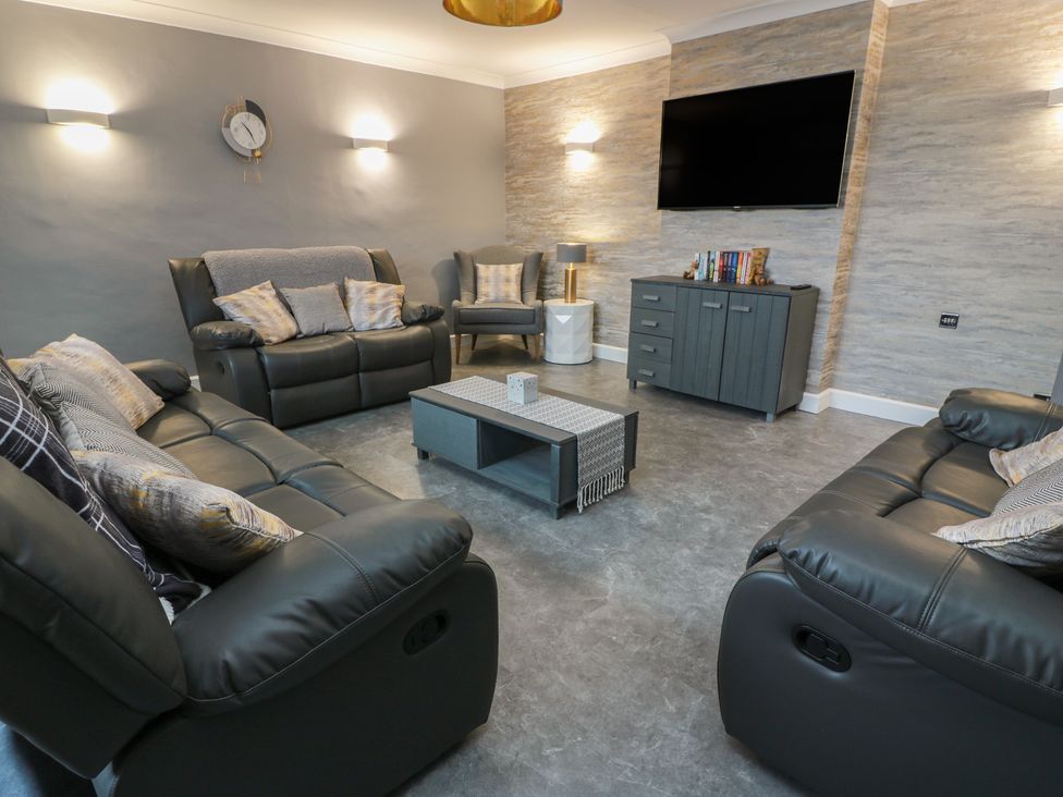 A living room with sofas and a television in Shotts Cottage Stirling