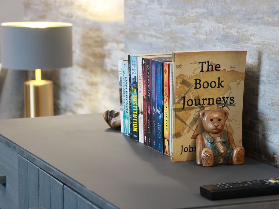 A living room with books and a lamp at Shotts Cottage in Stirling