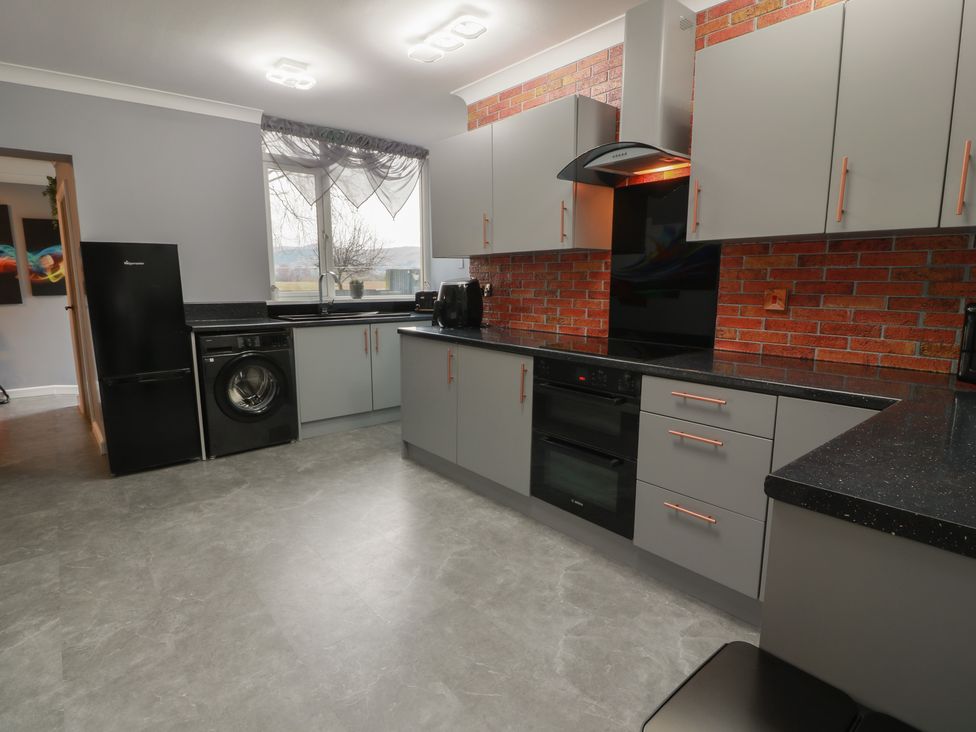 A kitchen with appliances including a refrigerator and washing machine at Shotts Cottage in Stirling